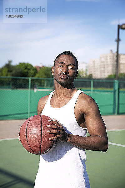Porträt eines selbstbewussten Spielers  der Basketball hält  während er vor Gericht steht