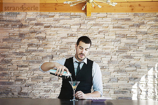 Mann gießt ein Getränk in Weinglas auf den Tisch an der Pool-Bar