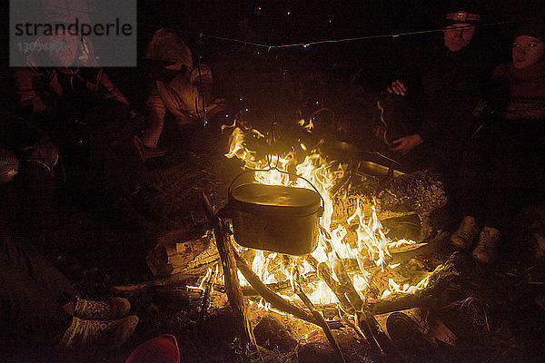 Freunde sitzen am Lagerfeuer auf dem Campingplatz