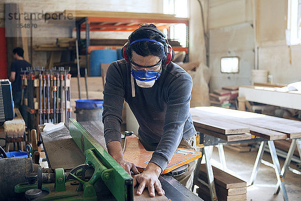 Zimmermann schneidet Holzbohlen in der Werkstatt