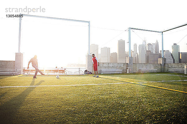 Vater spielt bei strahlendem Sonnenschein mit Mann auf dem Feld Fussball