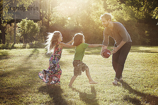 Mann spielt mit Kindern auf dem Rasen Fussball