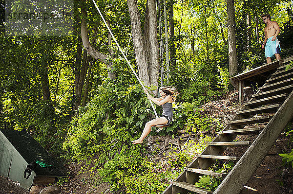 Fröhliche Frau schwingt am Seil im Wald