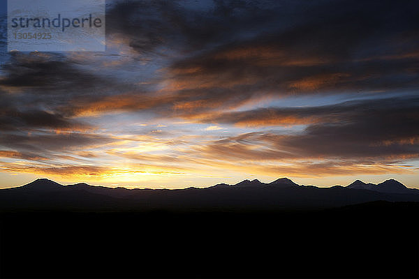 Landschaftliche Ansicht von Silhouettenbergen vor bewölktem Himmel bei Sonnenuntergang