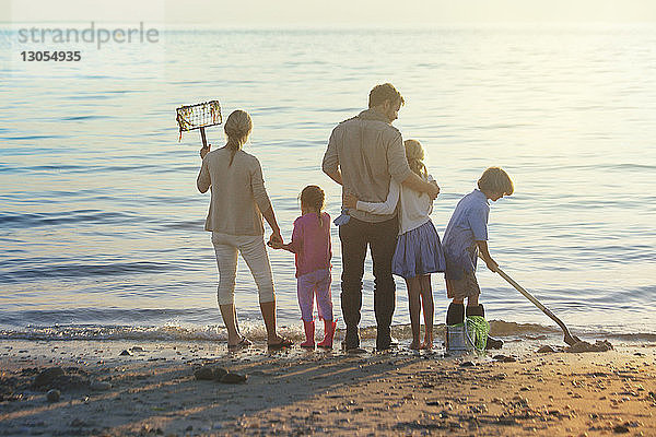 Familie reinigt Strand bei Sonnenuntergang