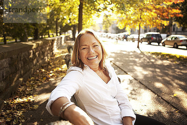 Porträt einer glücklichen älteren Frau am Strassenrand sitzend