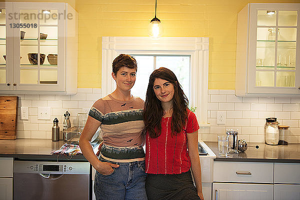 Porträt von glücklichen Freundinnen  die vor der Küchentheke stehen