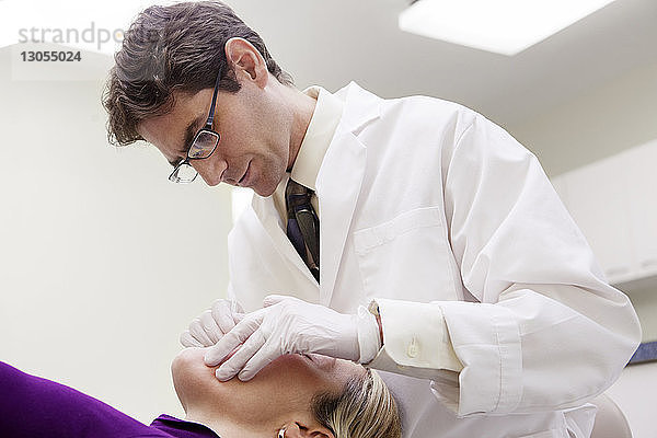 Niedrigwinkelansicht eines Zahnarztes  der den Patienten in der Klinik untersucht