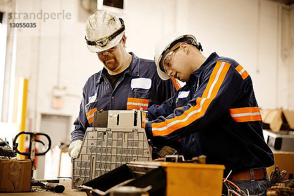 Männliche Arbeiter untersuchen elektrische Geräte in Recycling-Anlage