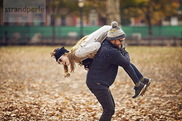 Mann trägt Frau auf der Schulter  während er im Park steht