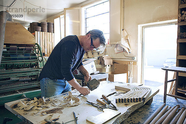 Männlicher Schreiner beim Holzmeisseln in der Werkstatt