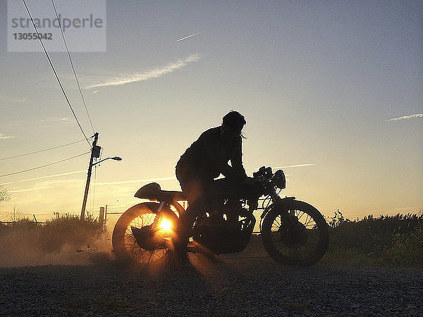 Silhouette eines Motorrad fahrenden Mannes gegen den Himmel