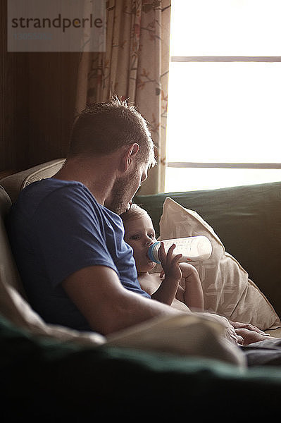 Vater küsst Sohn  während er zu Hause auf dem Sofa sitzt