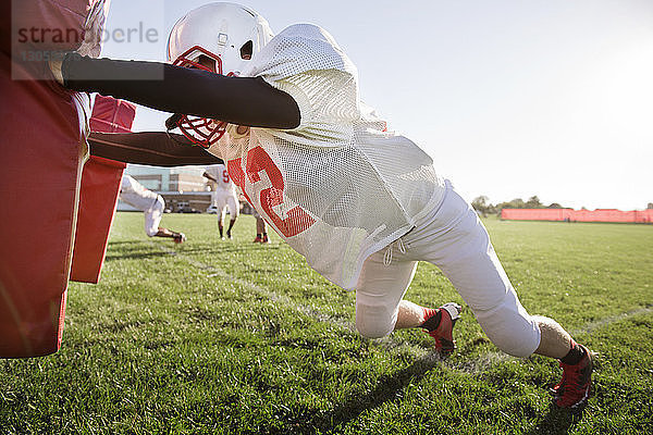 American-Footballer schiebt Football-Schlitten auf dem Feld