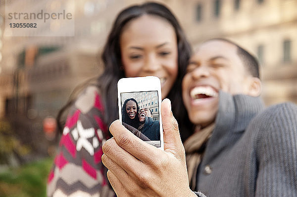 Fröhliches junges Paar klickt mit Smartphone auf Selfie