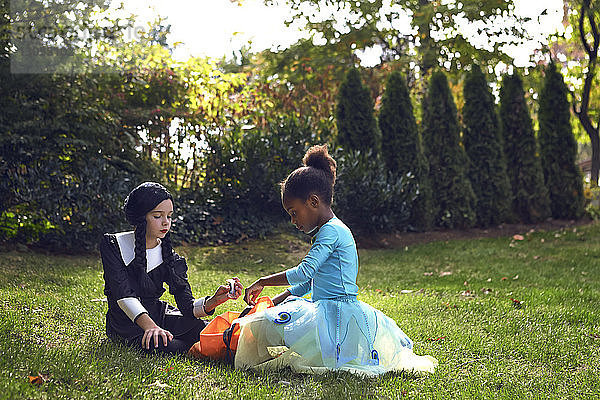 Mädchen in Kostümen sitzen auf dem Feld im Rasen