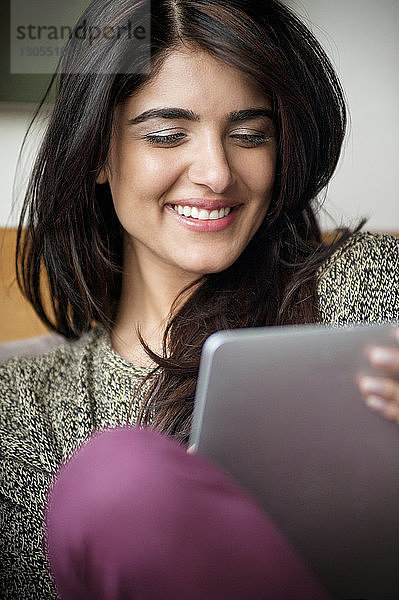 Nahaufnahme einer lächelnden Frau mit digitalem Tablet zu Hause