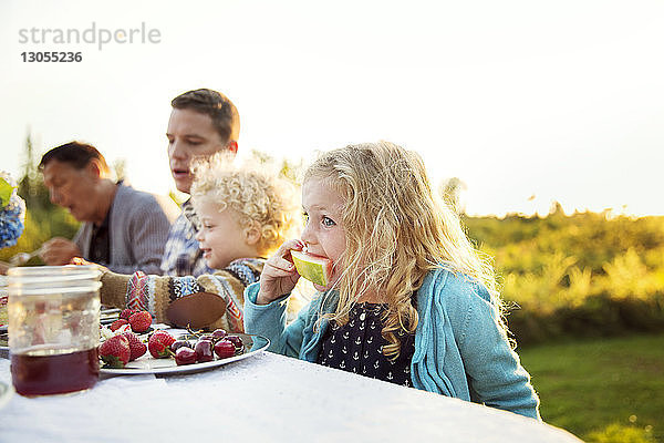 Mädchen isst Wassermelone mit der Familie auf dem Picknicktisch
