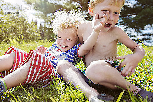 Porträt von glücklichen Geschwistern  die sich auf einem Grasfeld vergnügen