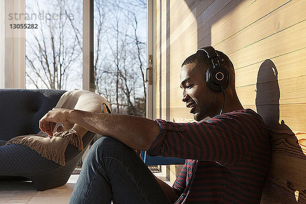 Glücklicher Mann hört Musik über Kopfhörer  während er zu Hause sitzt