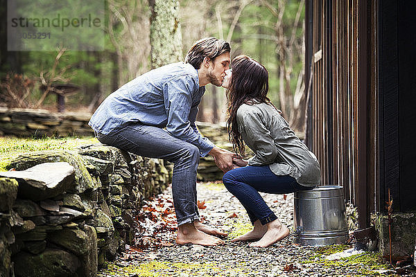 Seitenansicht eines Paares  das sich auf den Mund küsst  während es an einer Hütte sitzt