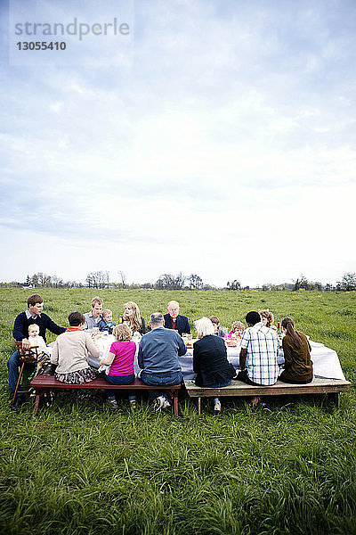 Familie und Freunde sitzen am Picknicktisch gegen den Himmel