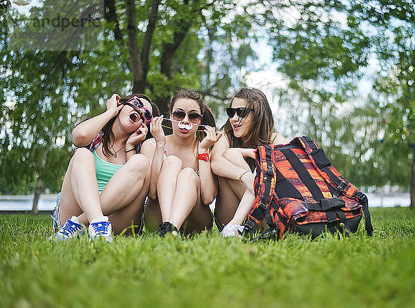 Freundinnen sitzen auf einem Grasfeld im Park