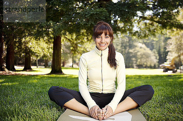Porträt einer glücklichen Frau  die im Park Yoga praktiziert