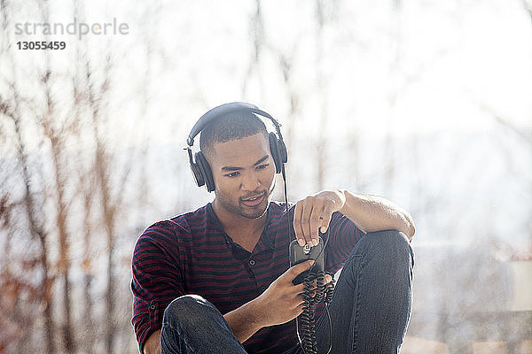 Mann hört Musik auf einem Smartphone  während er zu Hause sitzt