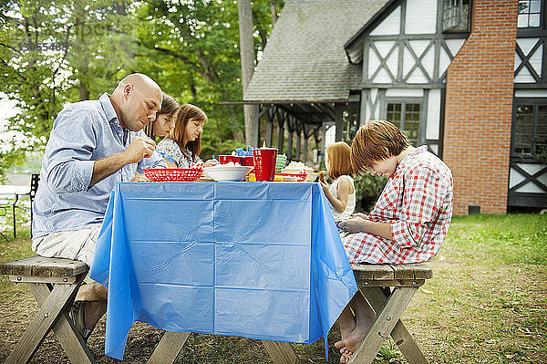 Familie beim Essen am Picknicktisch gegen Haus