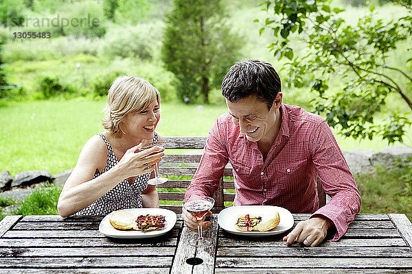 Glückliches Paar beim Essen am Tisch auf dem Feld