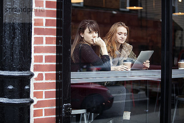 Freunde entspannen sich im Café durch ein Glasfenster gesehen