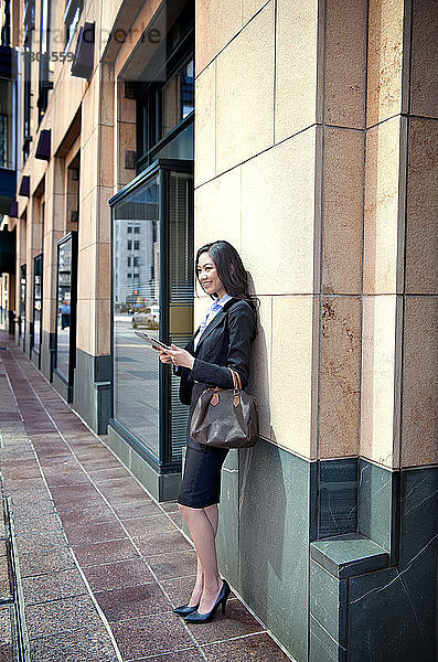 Seitenansicht einer lächelnden Geschäftsfrau  die auf einem Fußweg steht