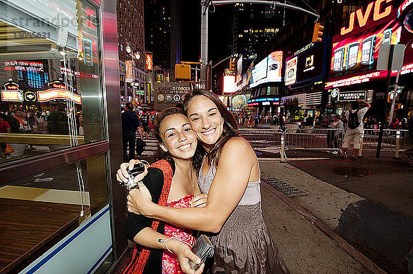 Porträt einer glücklichen Mutter  die ihre Tochter am Times Square umarmt