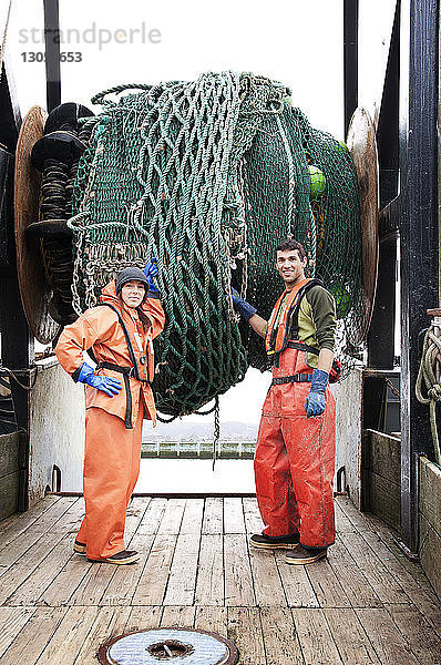 Porträt eines Mannes und einer Frau  die ein Netz halten und auf einem Fischerboot stehen