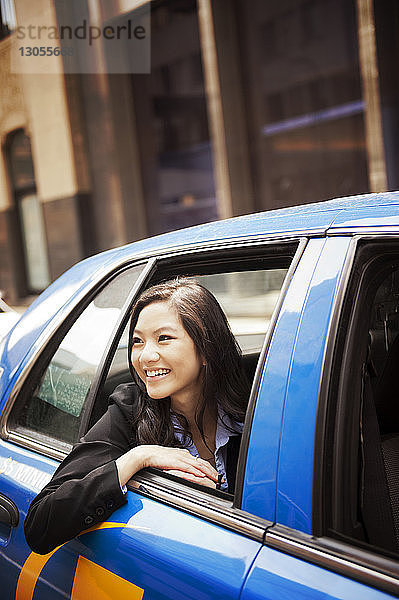 Nahaufnahme einer glücklichen Geschäftsfrau  die durch ein Autofenster schaut