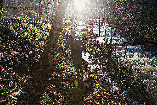 Wanderer mit Rucksack beim Wandern auf einem Hügel am Fluss