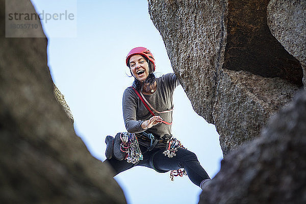 Niedrigwinkelansicht einer glücklichen Frau beim Felsklettern