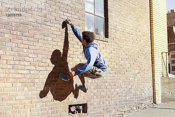 Mann klettert an Ziegelmauer