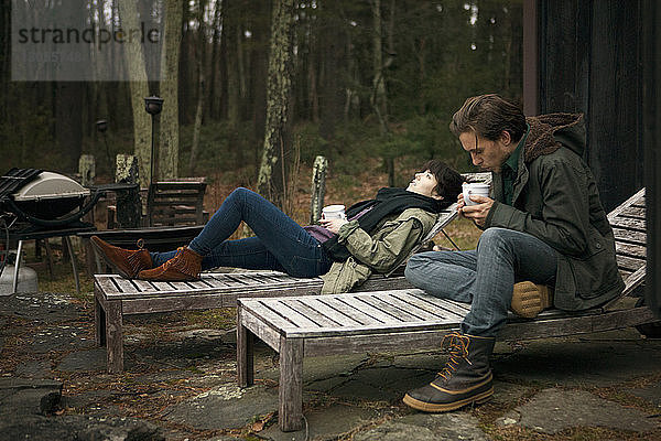 Ein Paar trinkt Kaffee  während es sich auf einem Liegestuhl auf dem Campingplatz entspannt