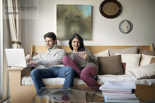 Junges Paar nutzt Technologien auf dem Sofa zu Hause