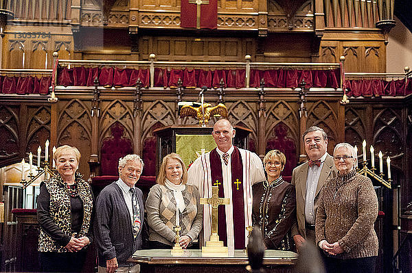 Porträt eines Priesters  der mit Menschen in der Kirche steht