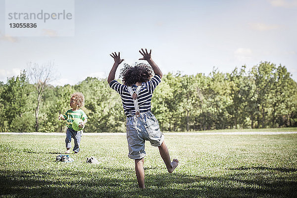 Geschwister spielen mit Ball im Hinterhof