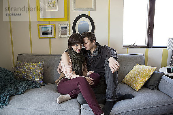 Romantisches Paar sitzt zu Hause auf dem Sofa