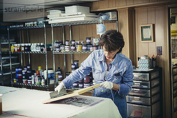 Handwerkerin untersucht Tintendrucke auf Stoff in einem Workshop
