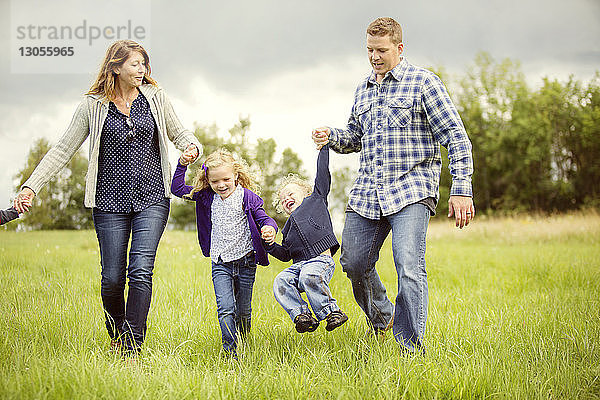 Glückliche Kinder mit Eltern  die sich auf dem Grasfeld vergnügen