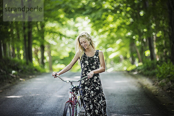 Lächelnde Frau mit Fahrrad auf der Straße