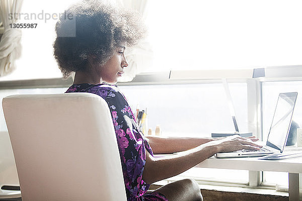 Seitenansicht einer Frau  die zu Hause einen Laptop-Computer benutzt