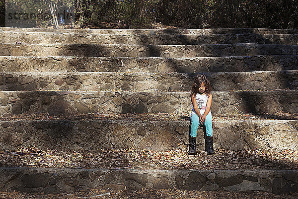 Trauriges Mädchen auf Steintreppe sitzend