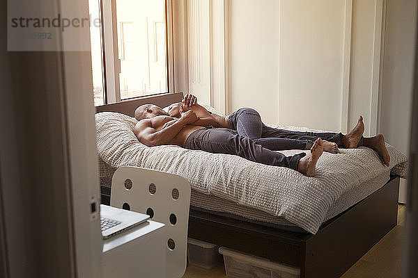 Paar in voller Länge auf dem Bett im Schlafzimmer zu Hause